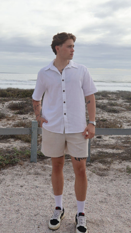 Natural linen men's shorts displayed on model with side pockets and elastic waistband