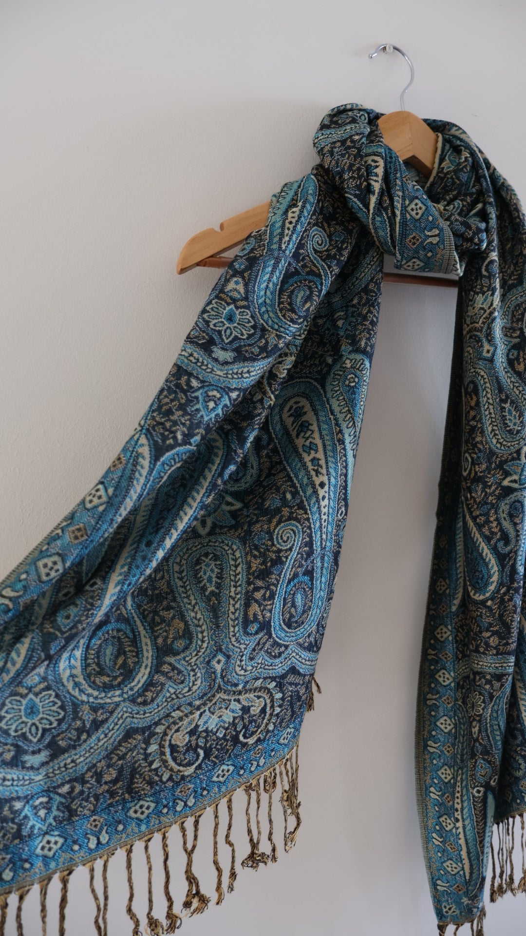 Blue boho festival pashmina scarf draped on a hanger, side 1.