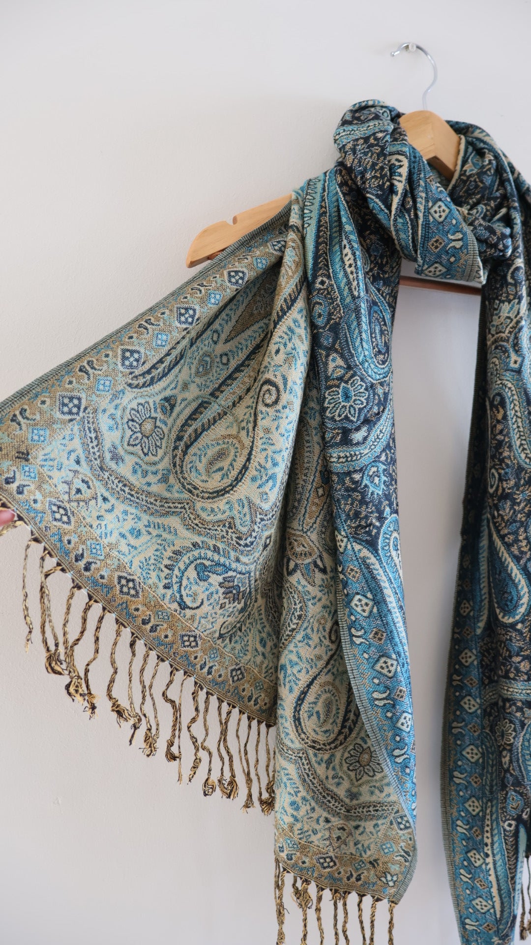 Blue boho festival pashmina scarf draped on a hanger, side 2.