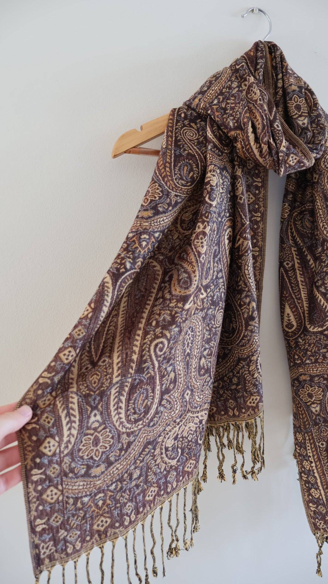 Brown boho festival pashmina scarf draped on a hanger, side 1.