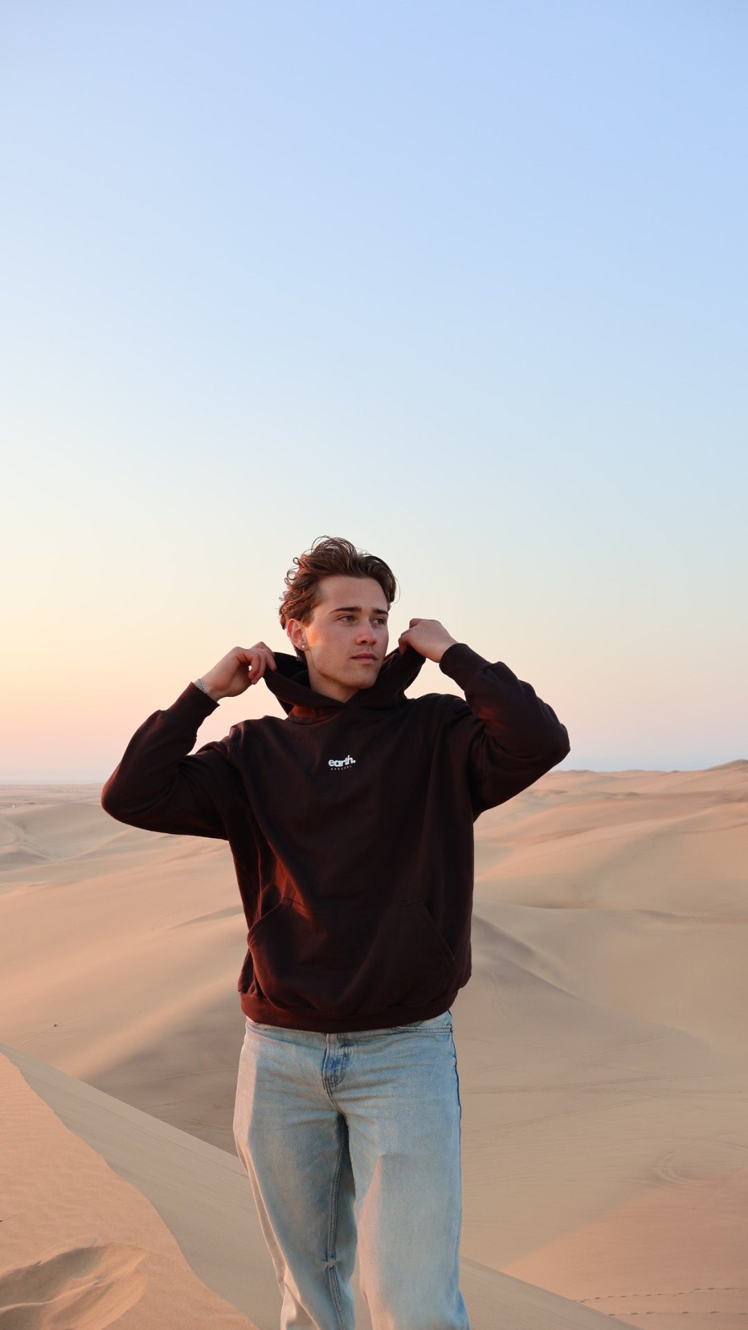 Person wearing a brown hoodie with a logo on a light blue background