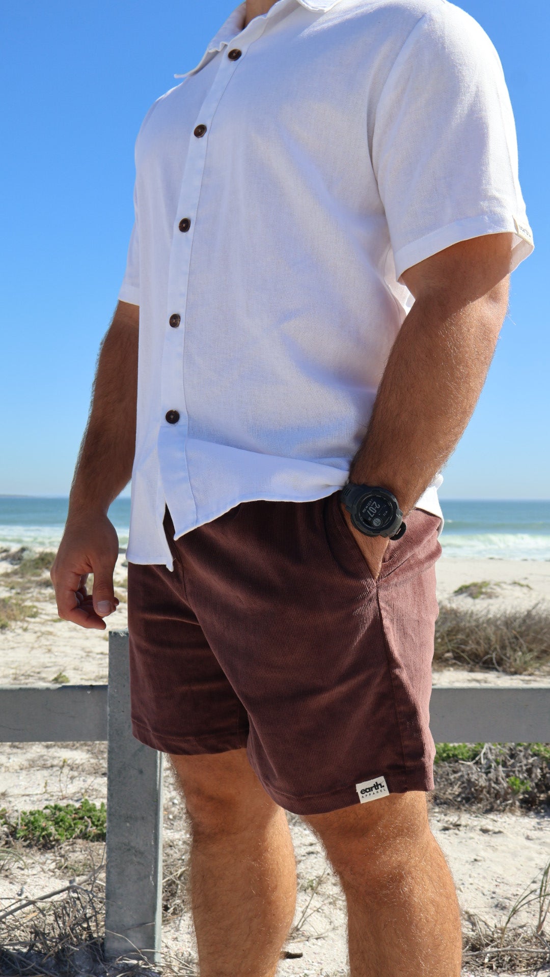 Men's corduroy shorts in earthy tones on model with visible texture, side pockets and elasticated waistband with drawstring.