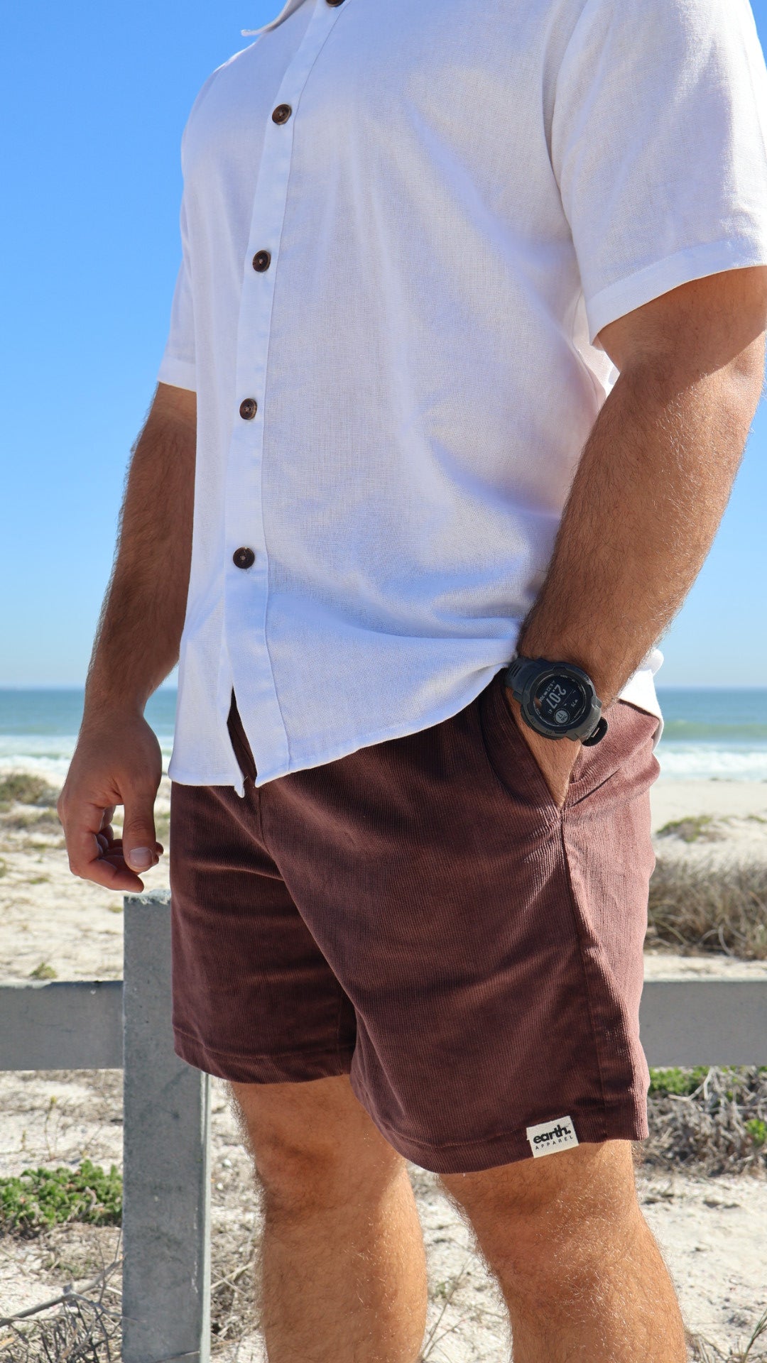 Men's corduroy shorts in earthy tones on model with visible texture, side pockets and elasticated waistband with drawstring.
