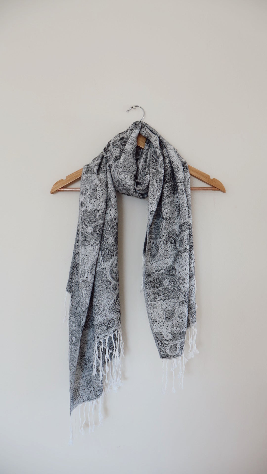 Grey and white boho festival pashmina scarf draped on a hanger