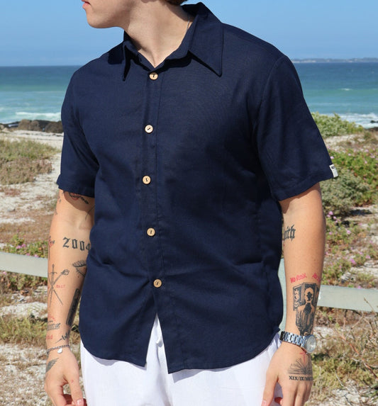 Person wearing a navy shirt with white pants against a blue sky.