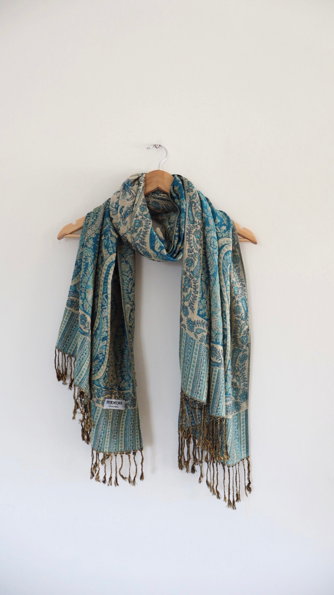 Turquoise boho festival pashmina scarf draped on a hanger