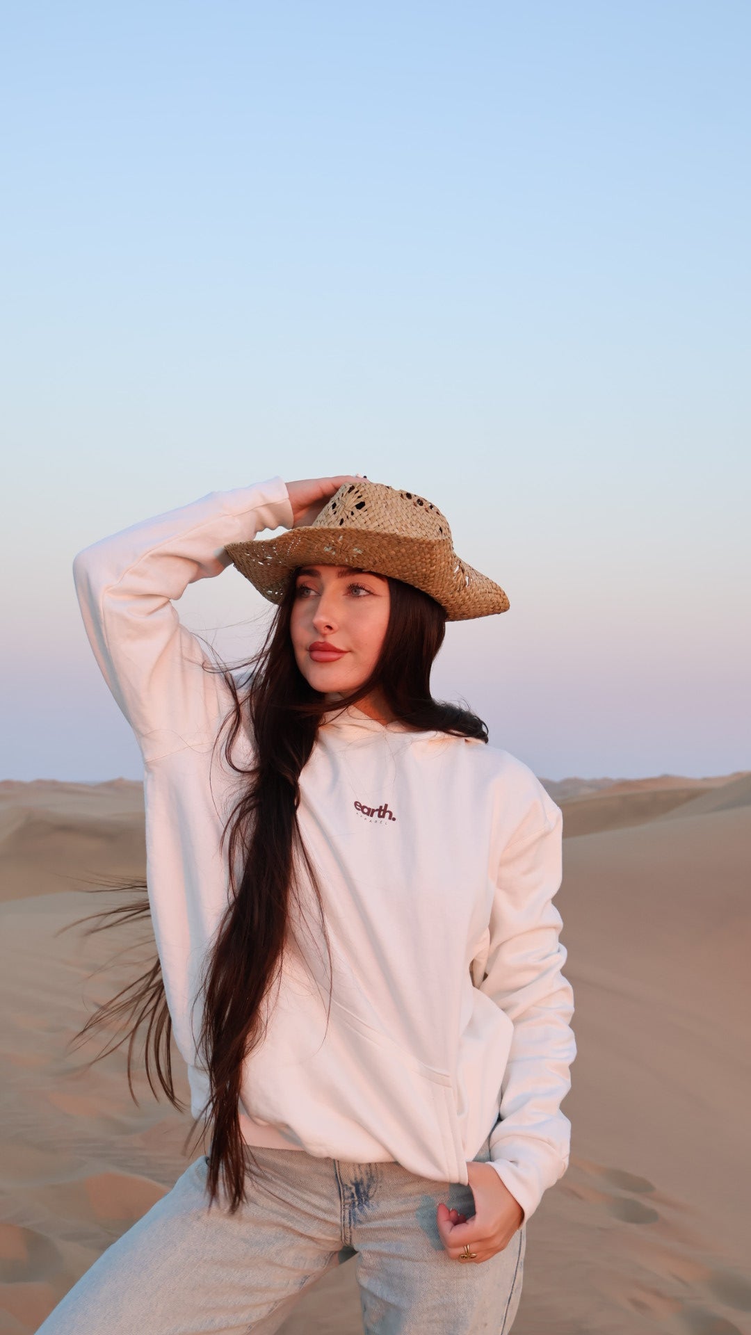 Person wearing a light-colored outfit with a straw hat against a gradient background