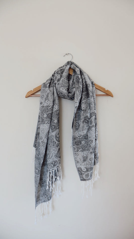 Grey and white boho festival pashmina scarf draped on a hanger
