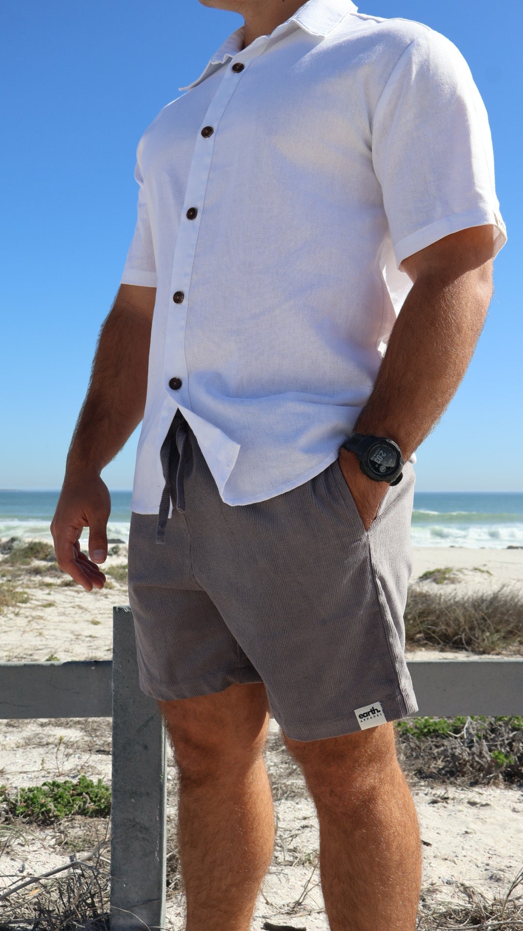 Men's corduroy shorts in earthy tones on model with visible texture, side pockets and elasticated waistband with drawstring.
