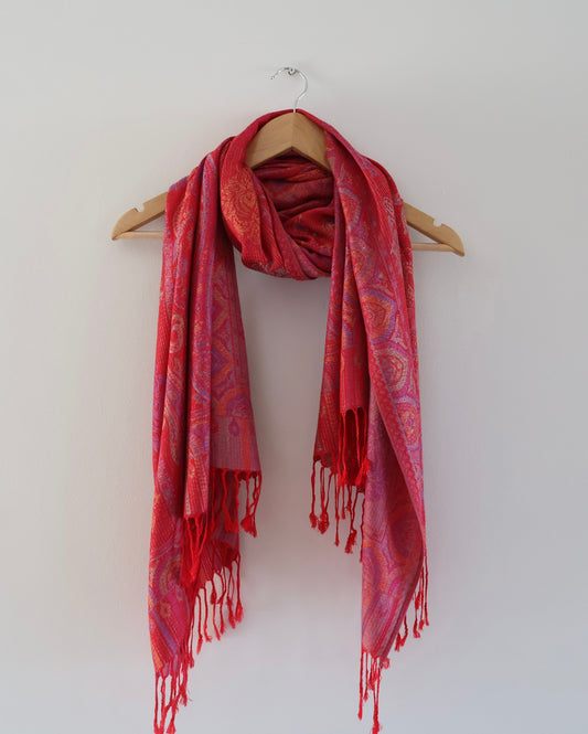 Red boho festival pashmina scarf draped on a hanger

